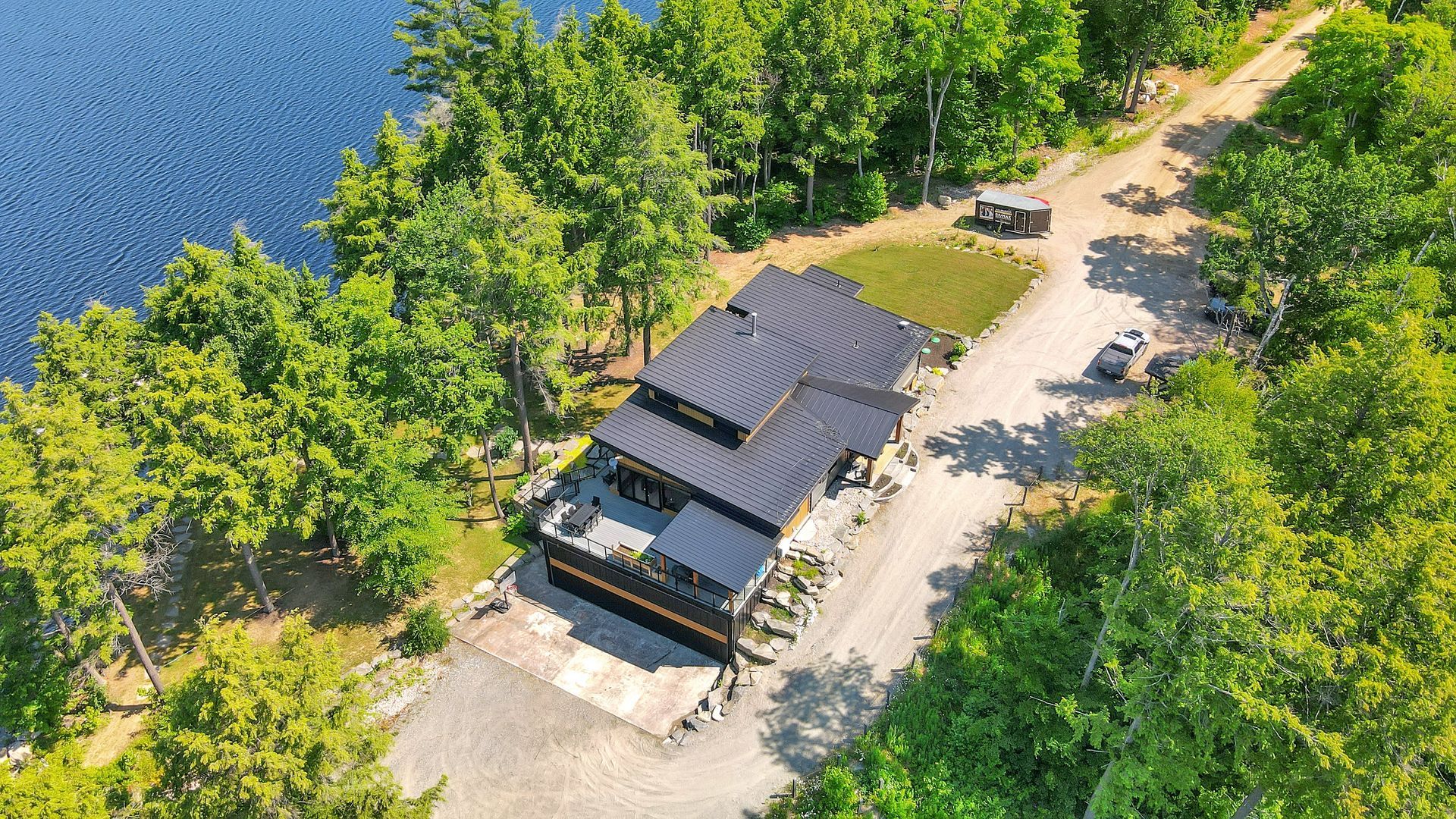 An aerial view of a house on a small island in the middle of a lake surrounded by trees.
