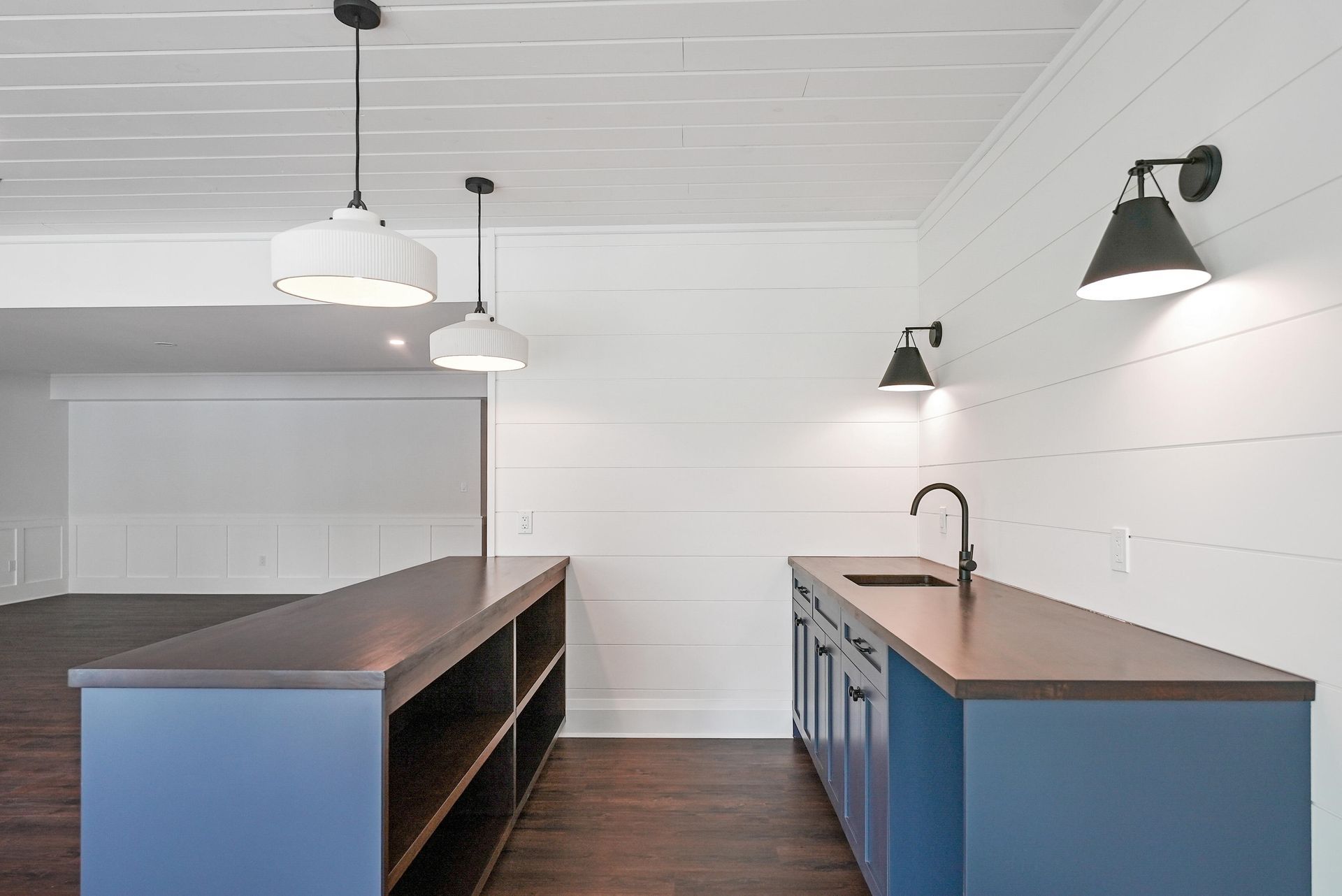 Modern kitchen with blue cabinets, wood counters, pendant lights, and dark flooring