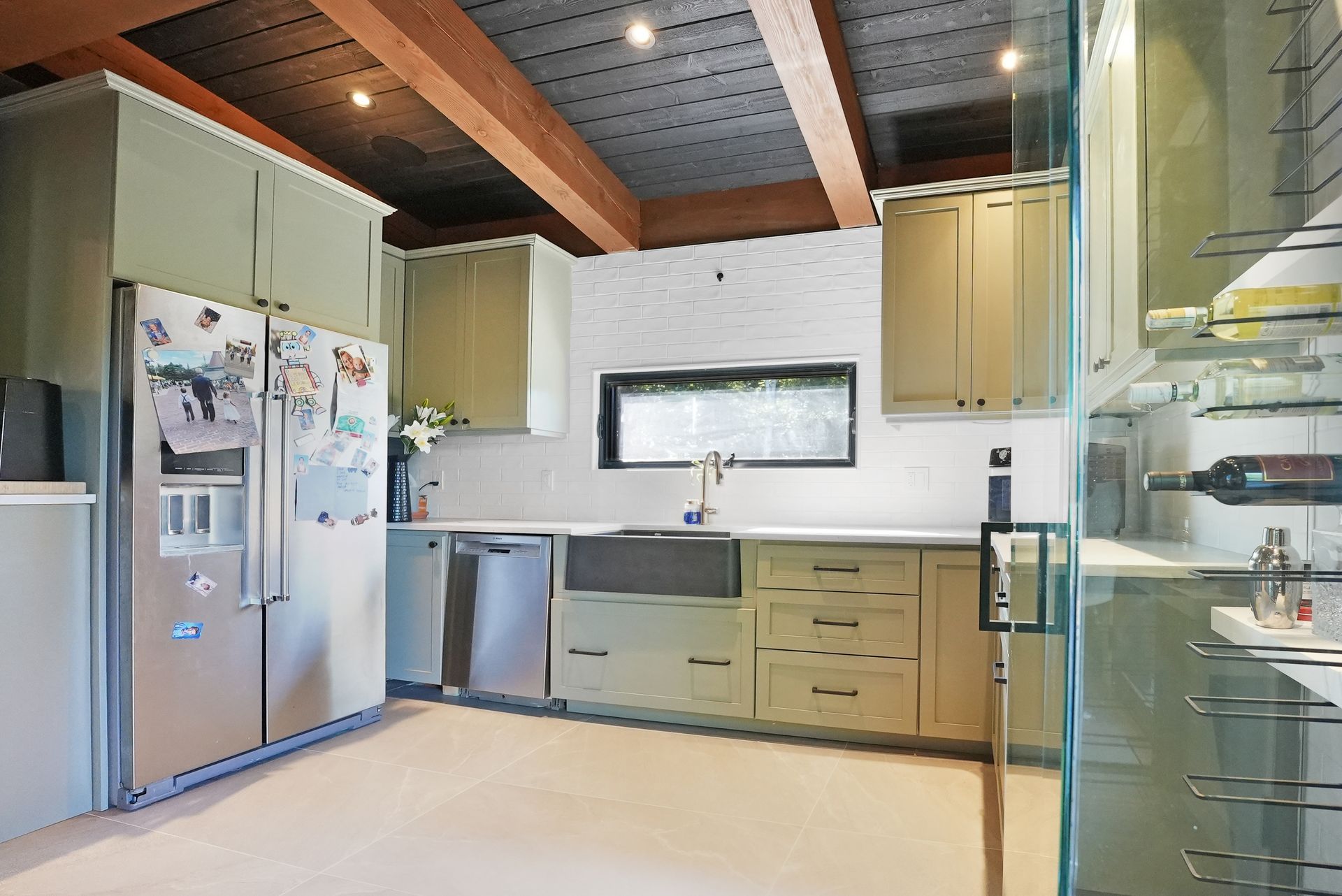 A living room with a table and chairs and a kitchen with wooden beams.