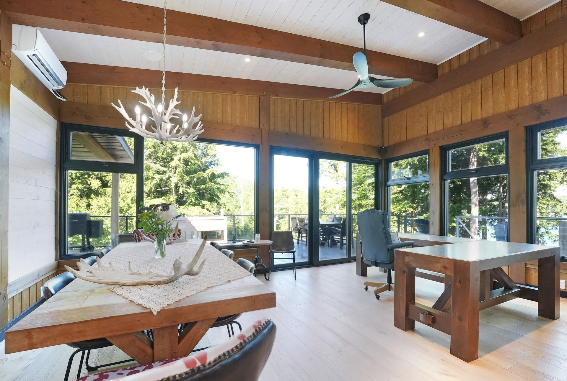 A living room with a table and chairs and a kitchen with wooden beams.