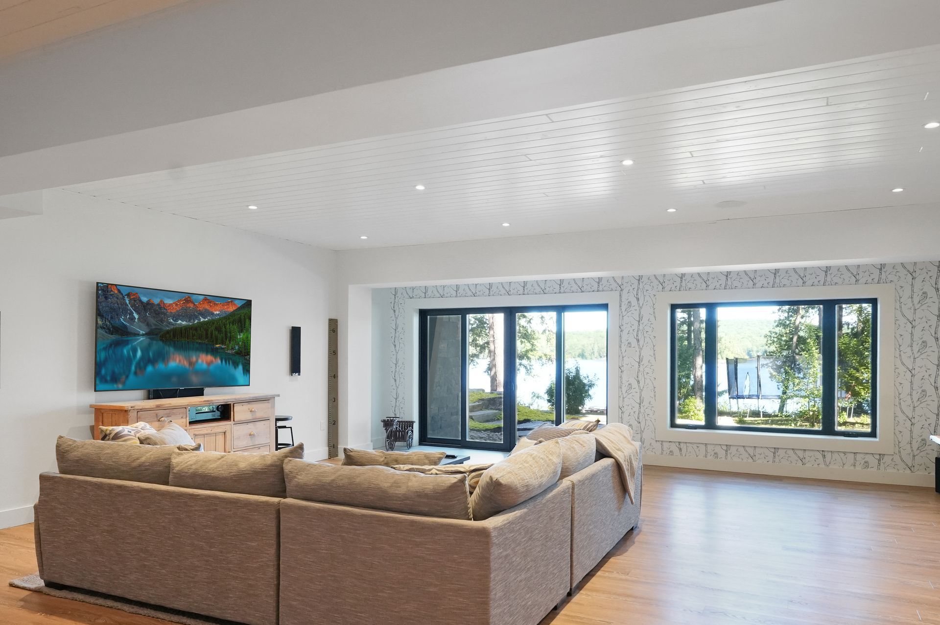 A game room with a bar , stools , a pool table and a flat screen tv.