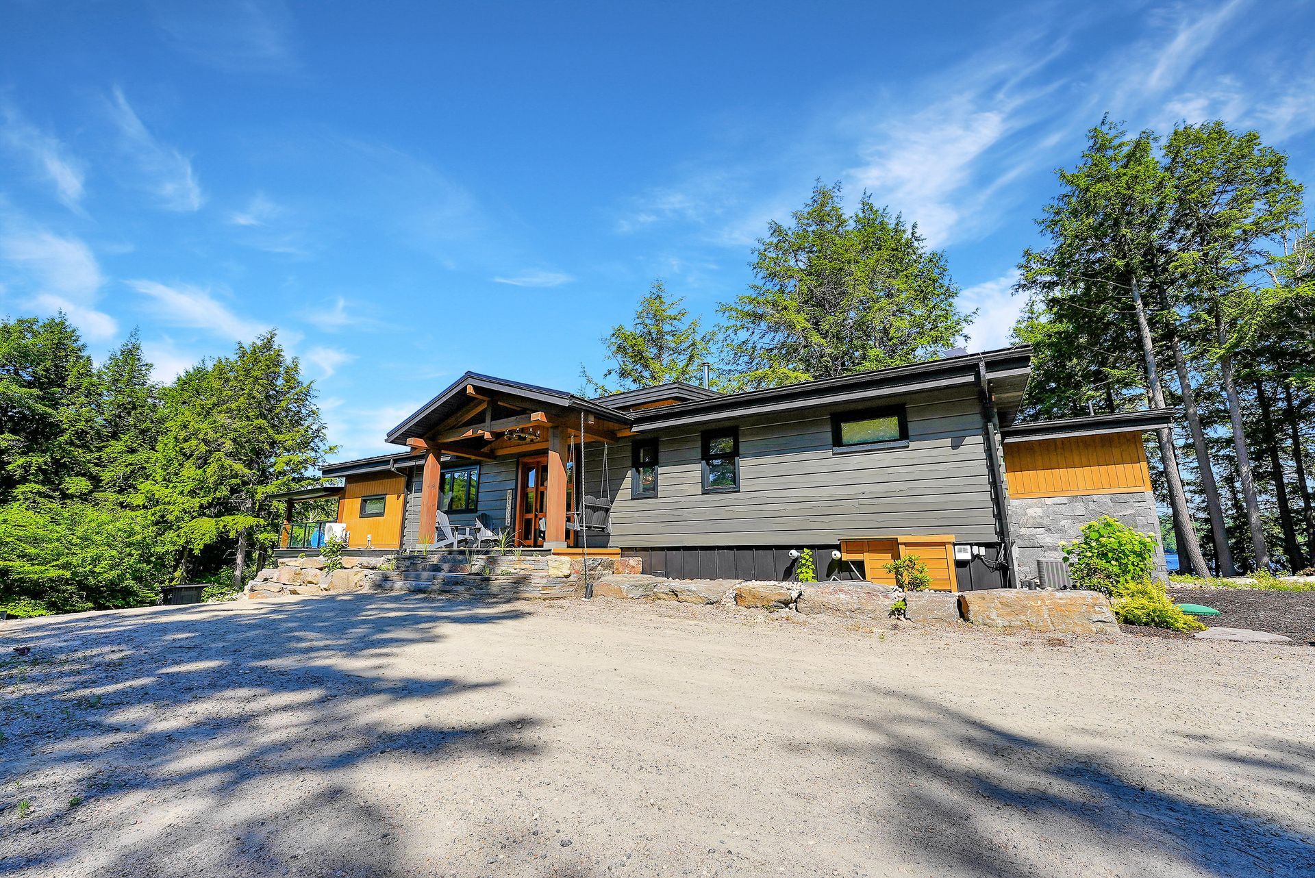 A small house with a porch in the middle of a forest.