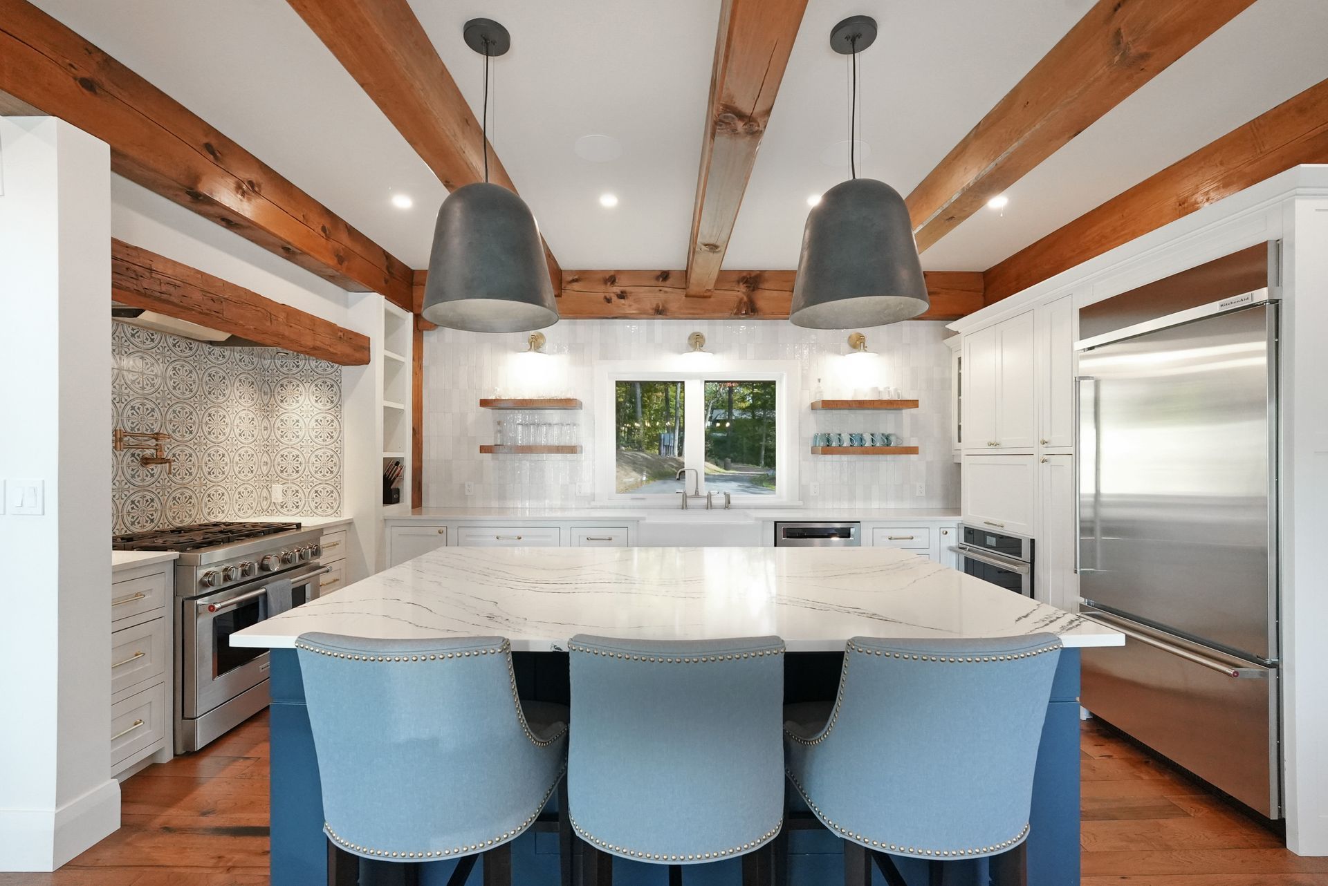 A living room with a table and chairs and a kitchen with wooden beams.