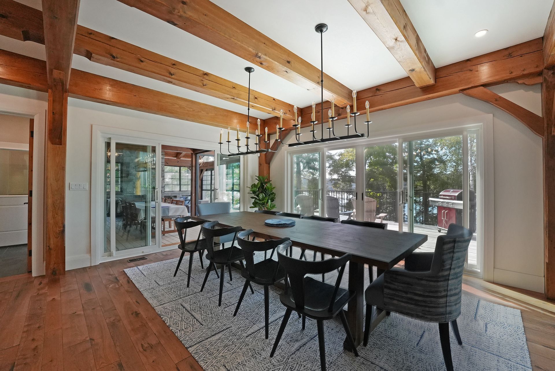 A living room with a table and chairs and a kitchen with wooden beams.