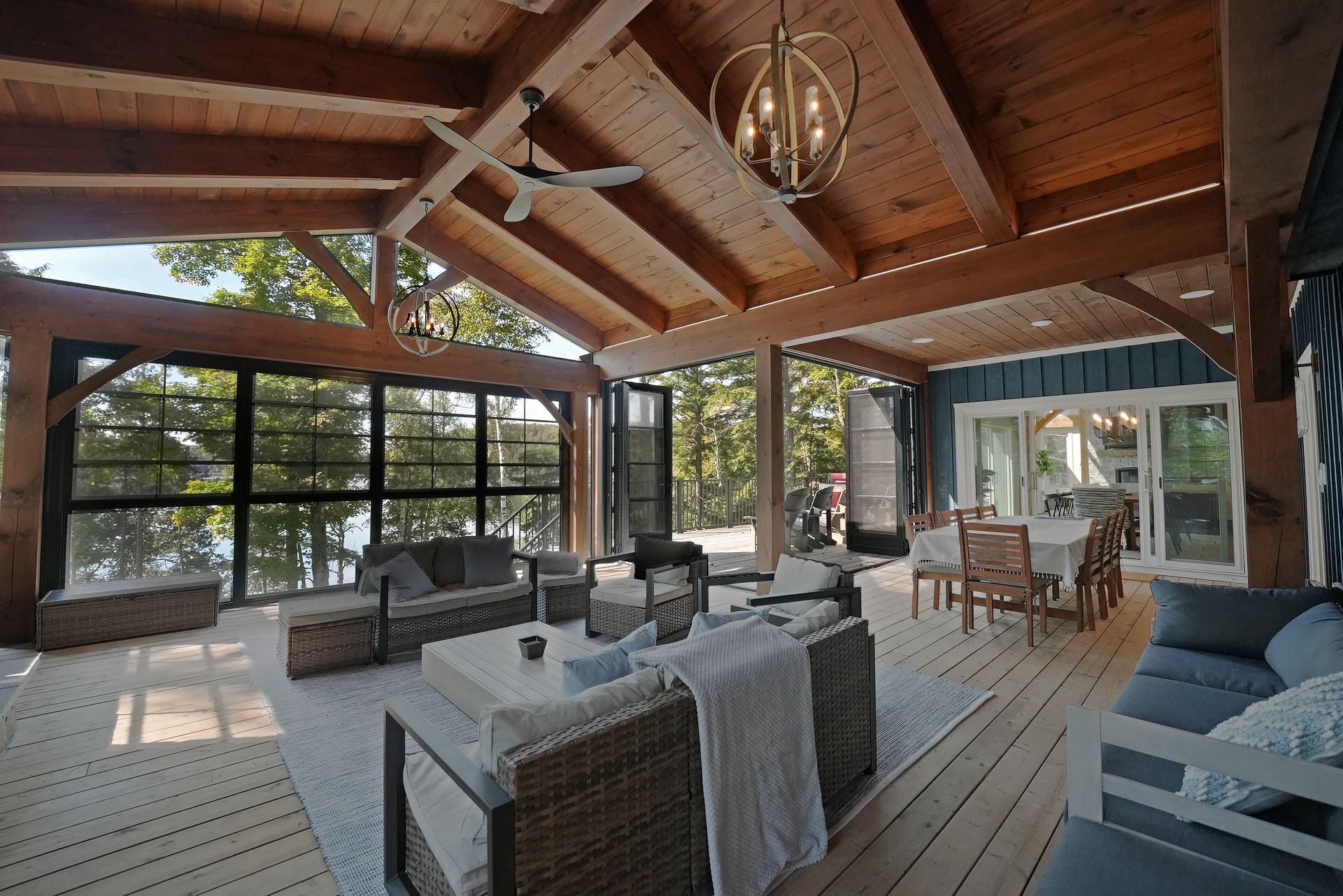 A deck with wicker furniture and umbrellas overlooking a lake