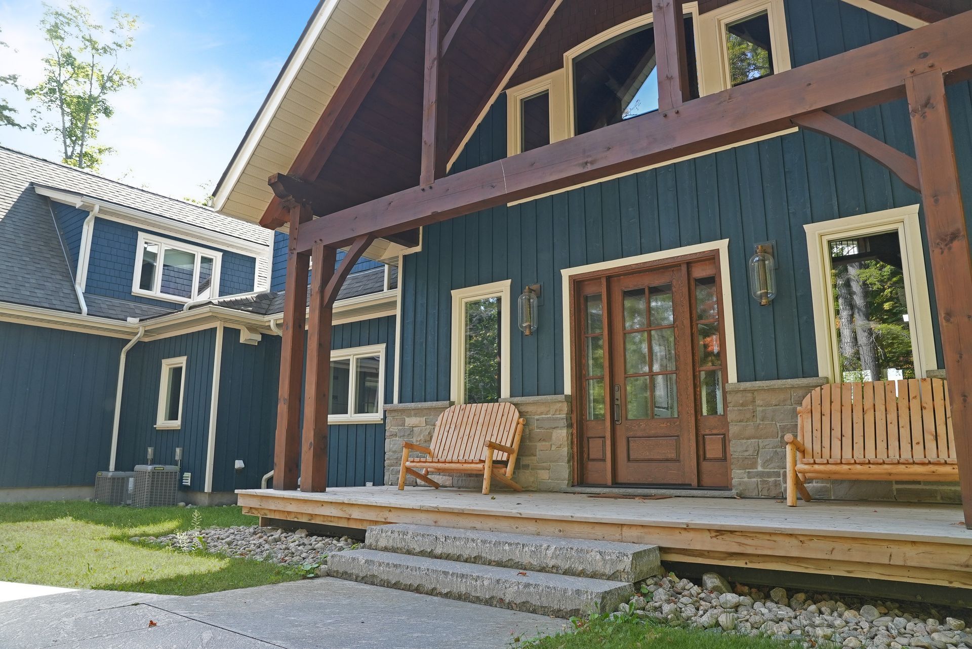 A deck with wicker furniture and umbrellas overlooking a lake