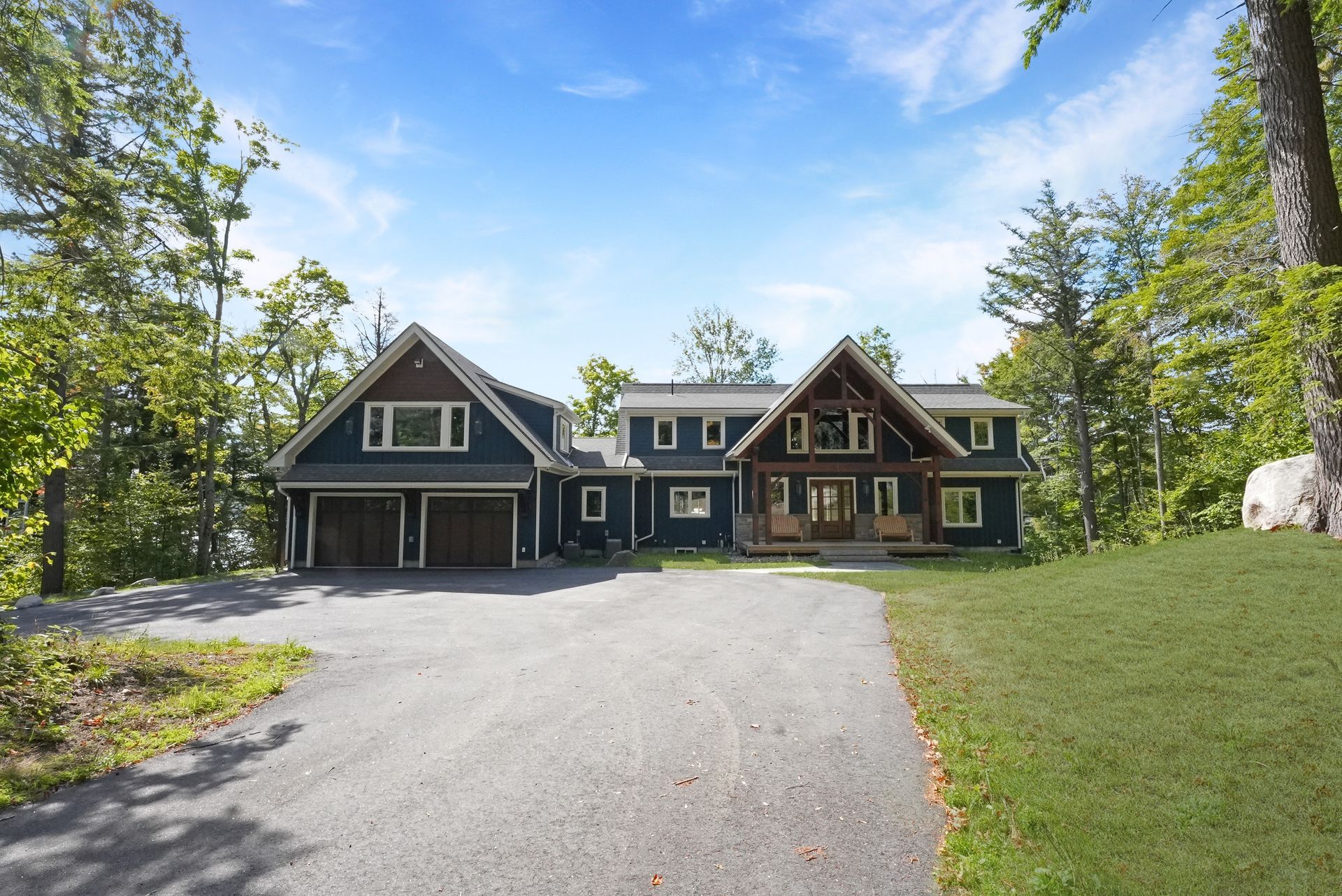 A large house with a lot of windows and a wooden door is surrounded by trees.