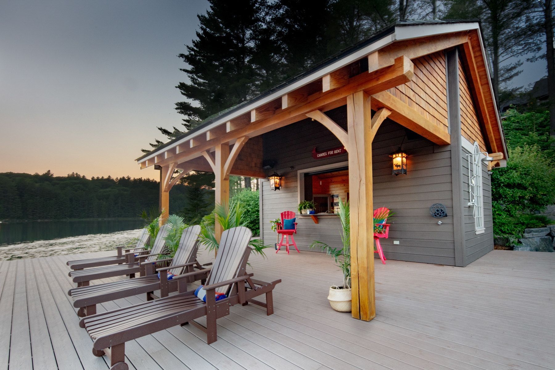 A row of lounge chairs are lined up on a deck in front of a house.
