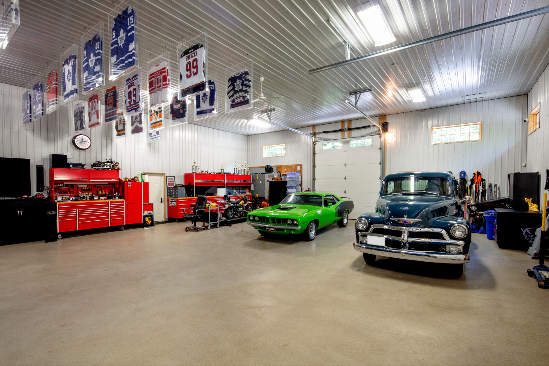 A garage with a green car and a blue truck in it.