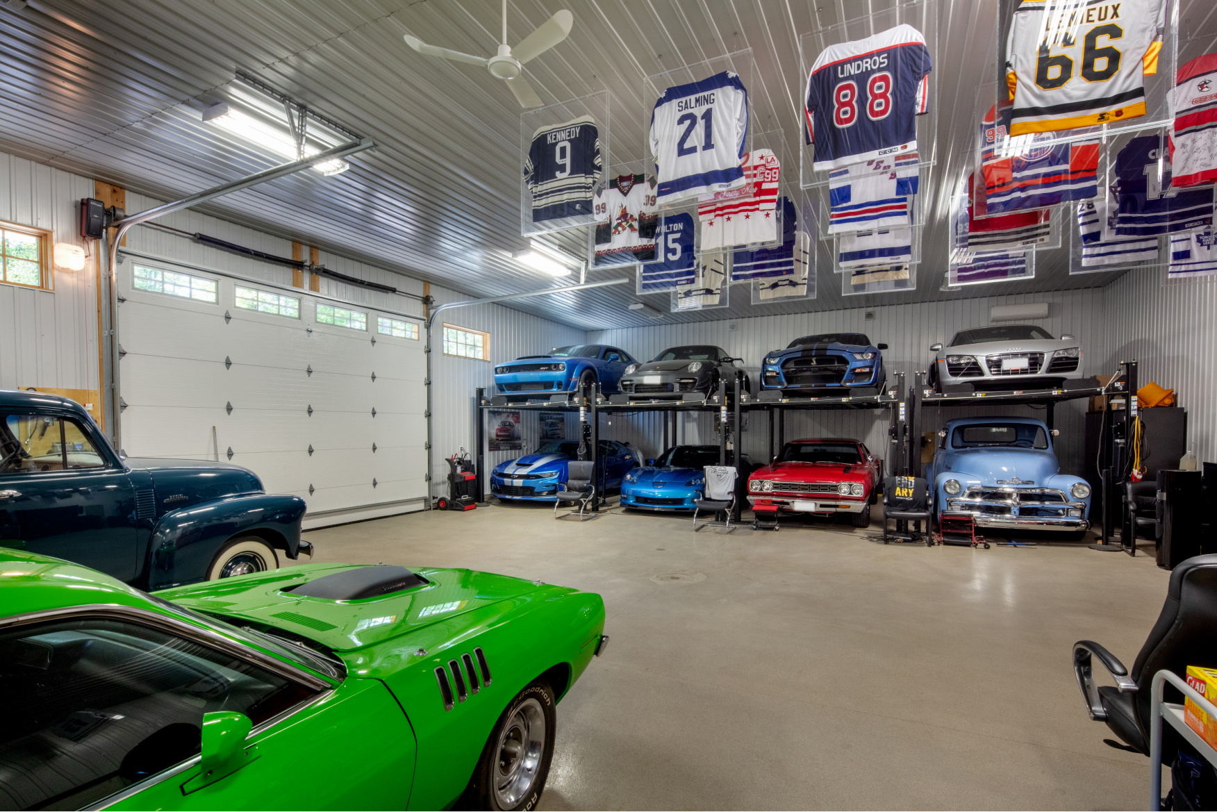 A garage filled with lots of cars and jerseys hanging from the ceiling.
