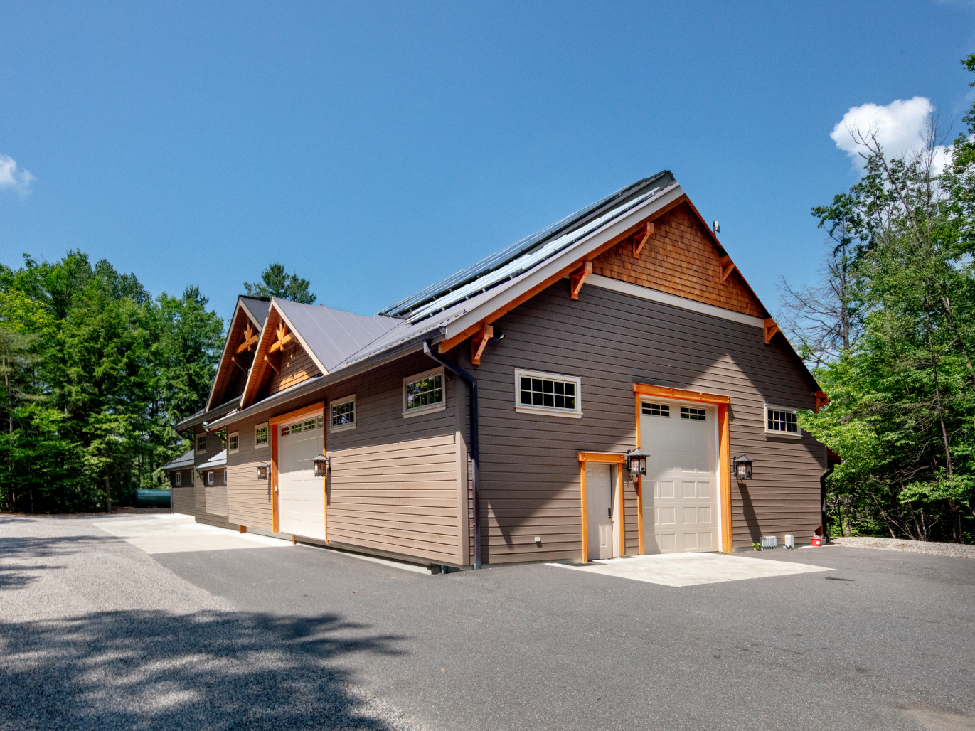 A large house with a lot of garage doors is surrounded by trees.