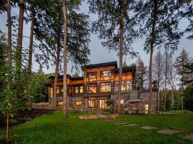 A patio with chairs and a table overlooking a lake in the woods.