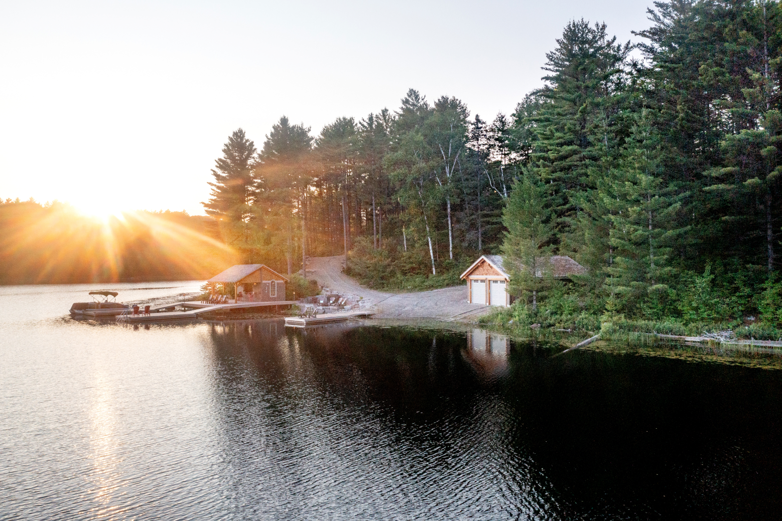 The sun is setting over a lake surrounded by trees.