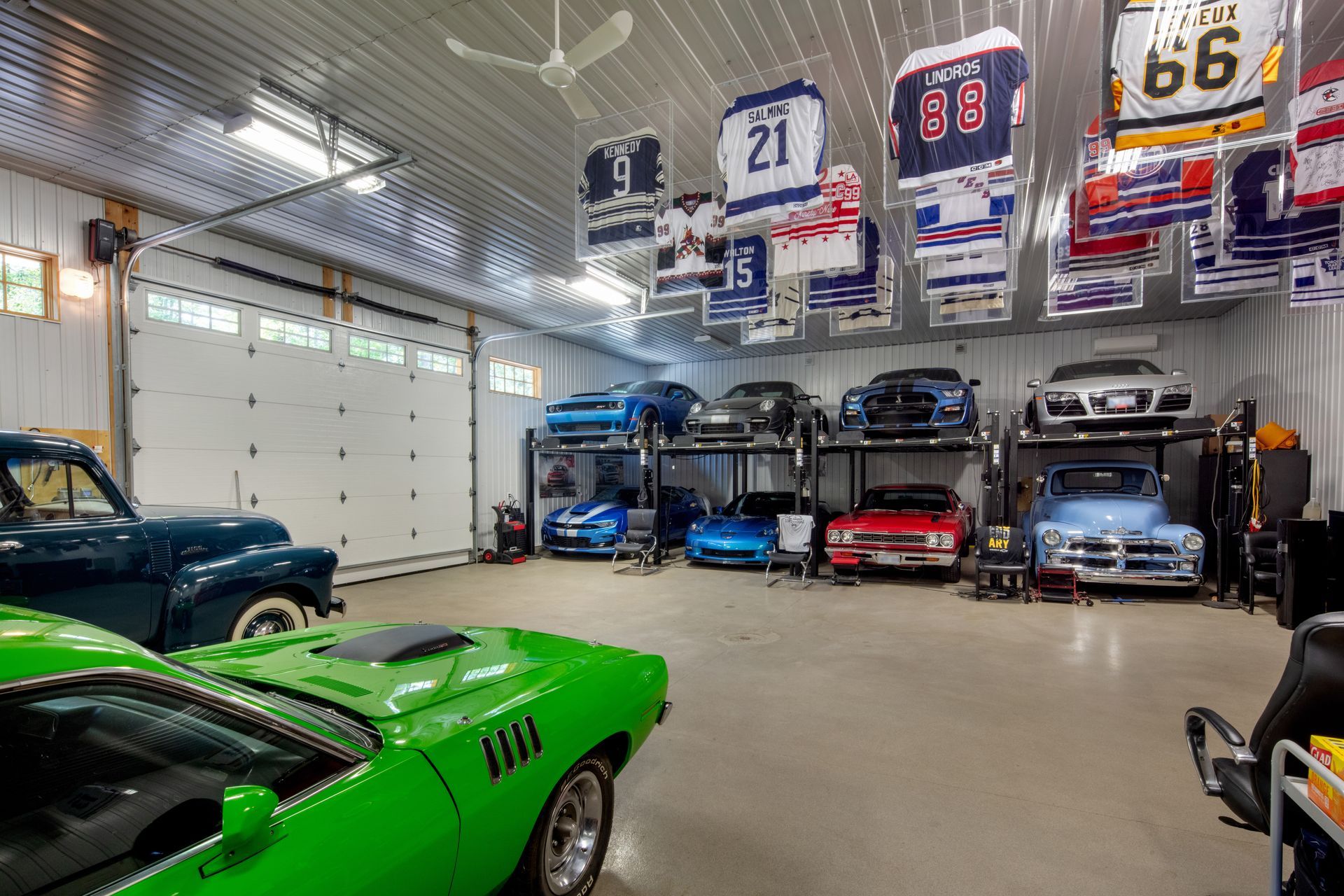 A garage filled with lots of cars and a green car.