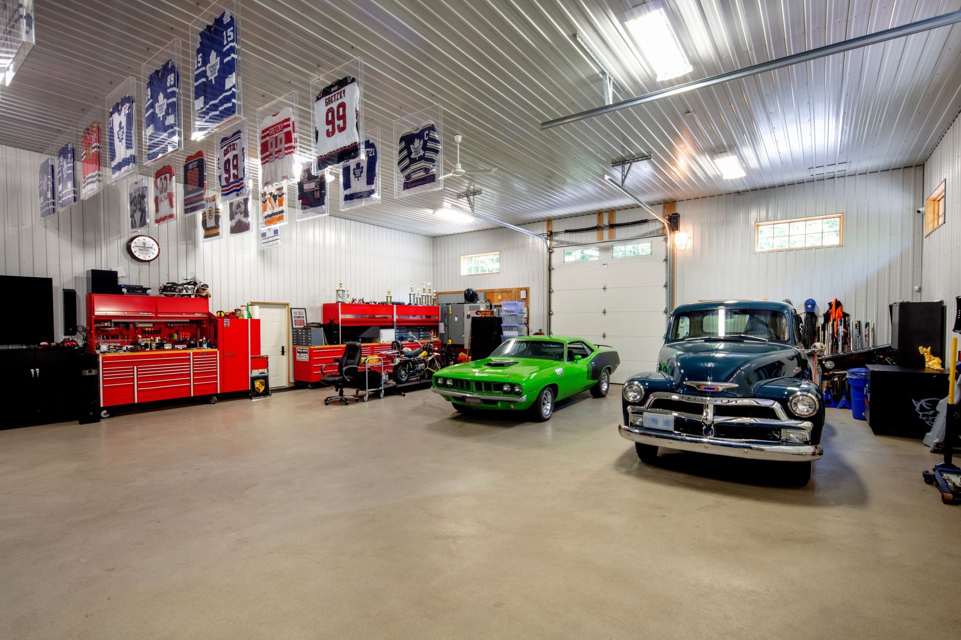 A green car and a blue truck are parked in a garage.