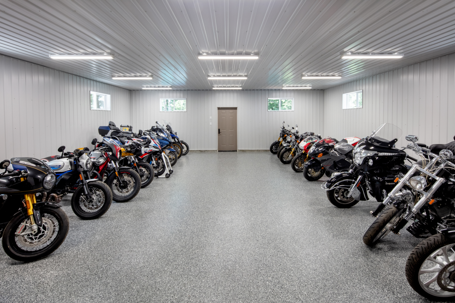 A row of motorcycles are parked in a garage.