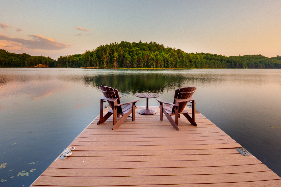 Two chairs are sitting on a dock overlooking a lake.