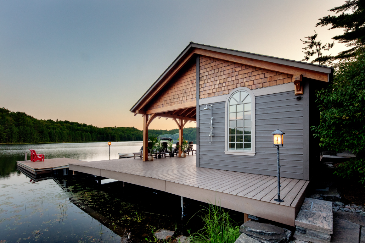 A small house is sitting on a dock next to a lake.