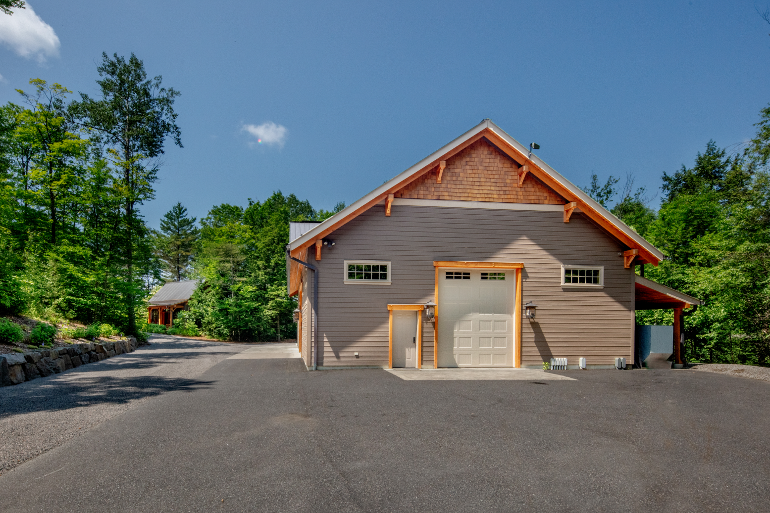 A garage with a wooden roof is surrounded by trees