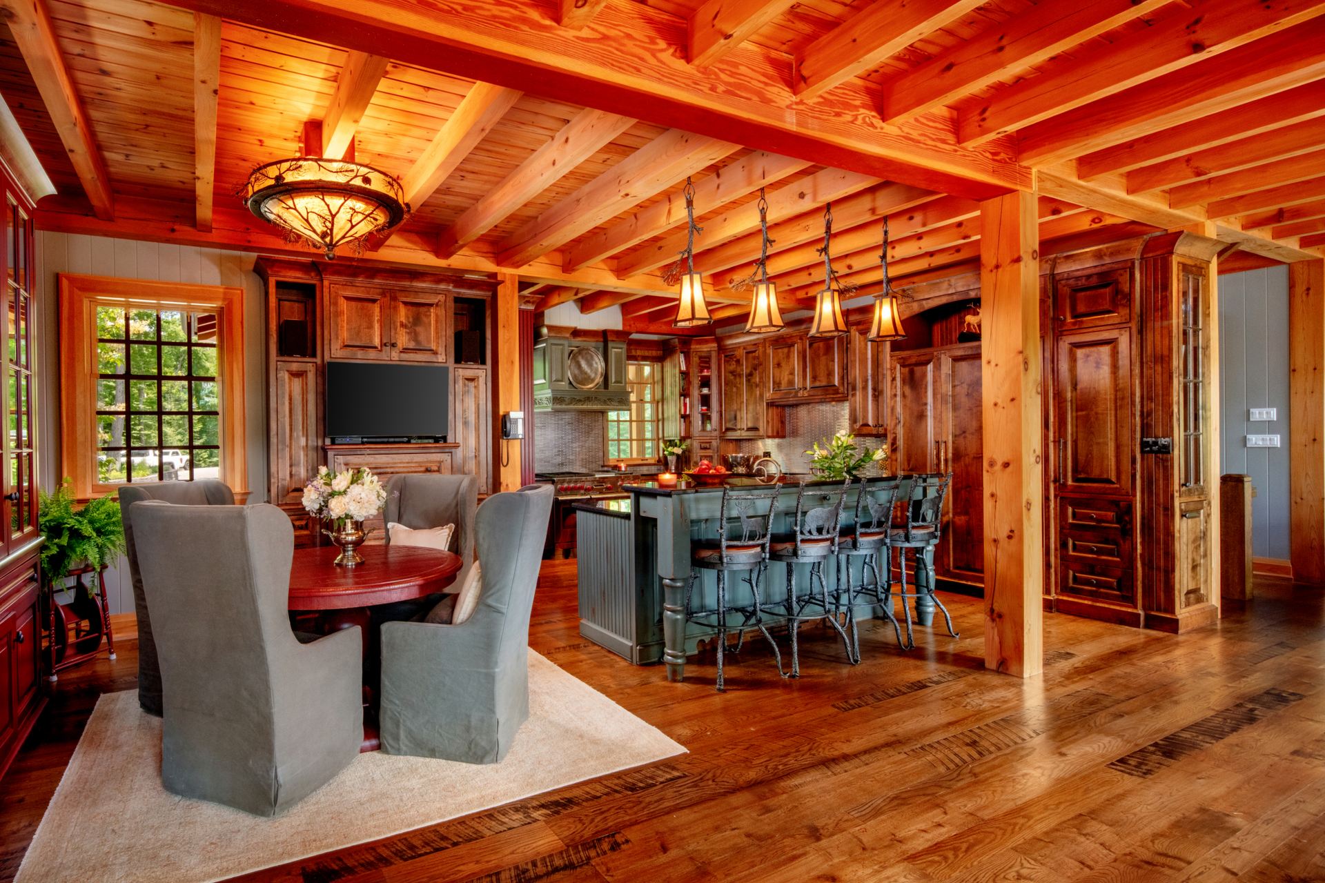 A living room with a table and chairs and a kitchen with wooden beams.