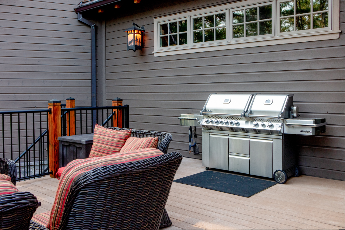 A patio with a grill , chairs , and a couch.