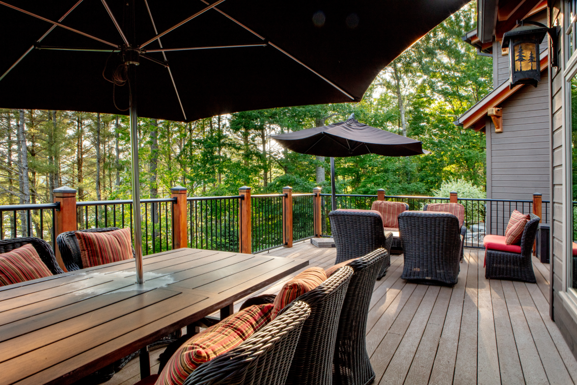 A large deck with a table and chairs and umbrellas.