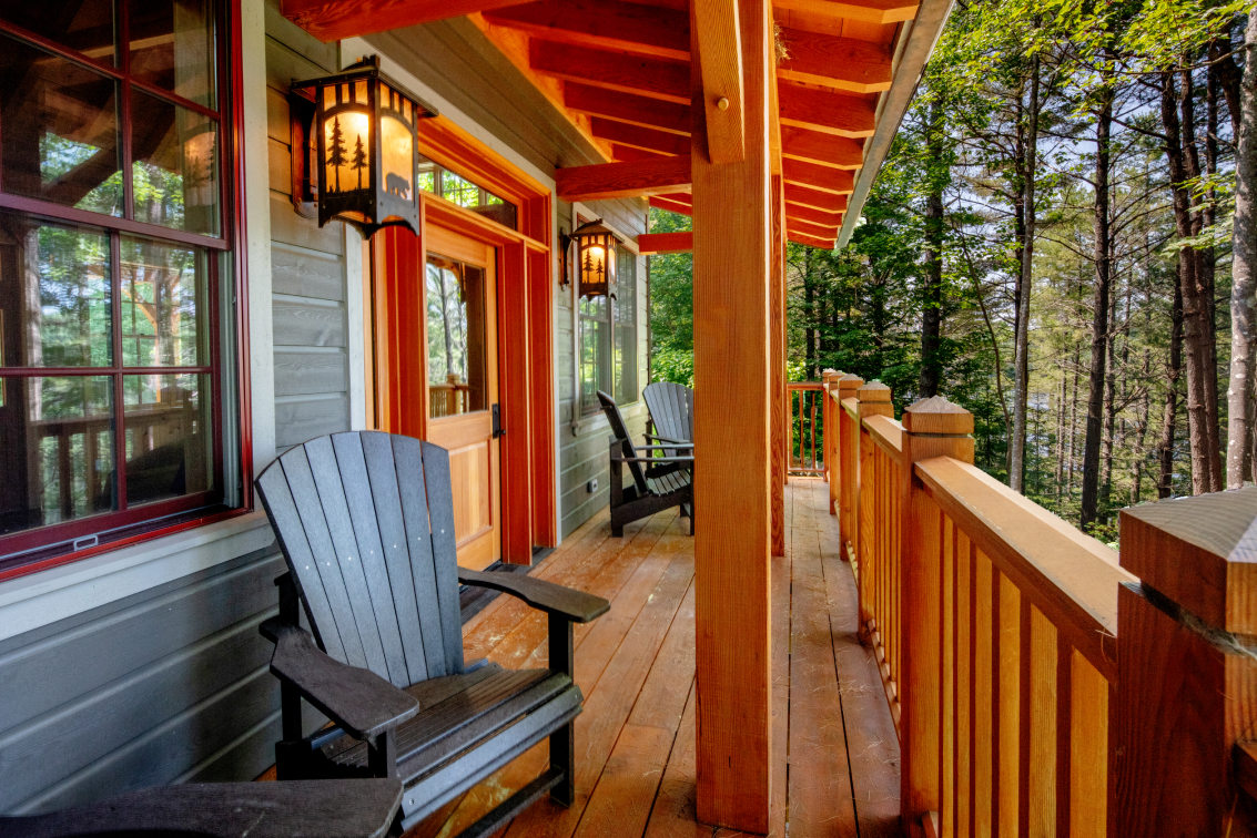There are two chairs on the porch of a house.
