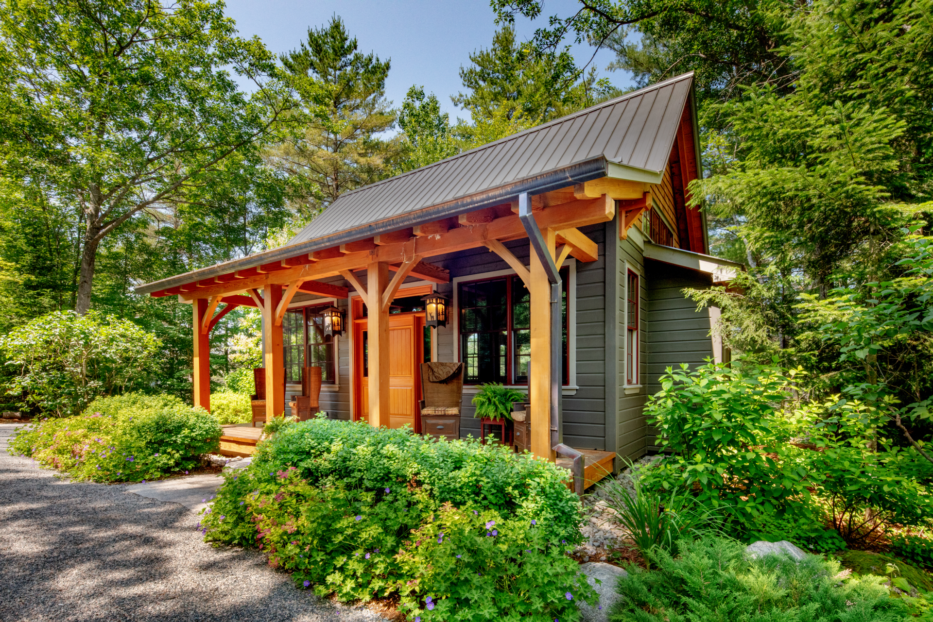 A small house with a porch in the middle of a forest.