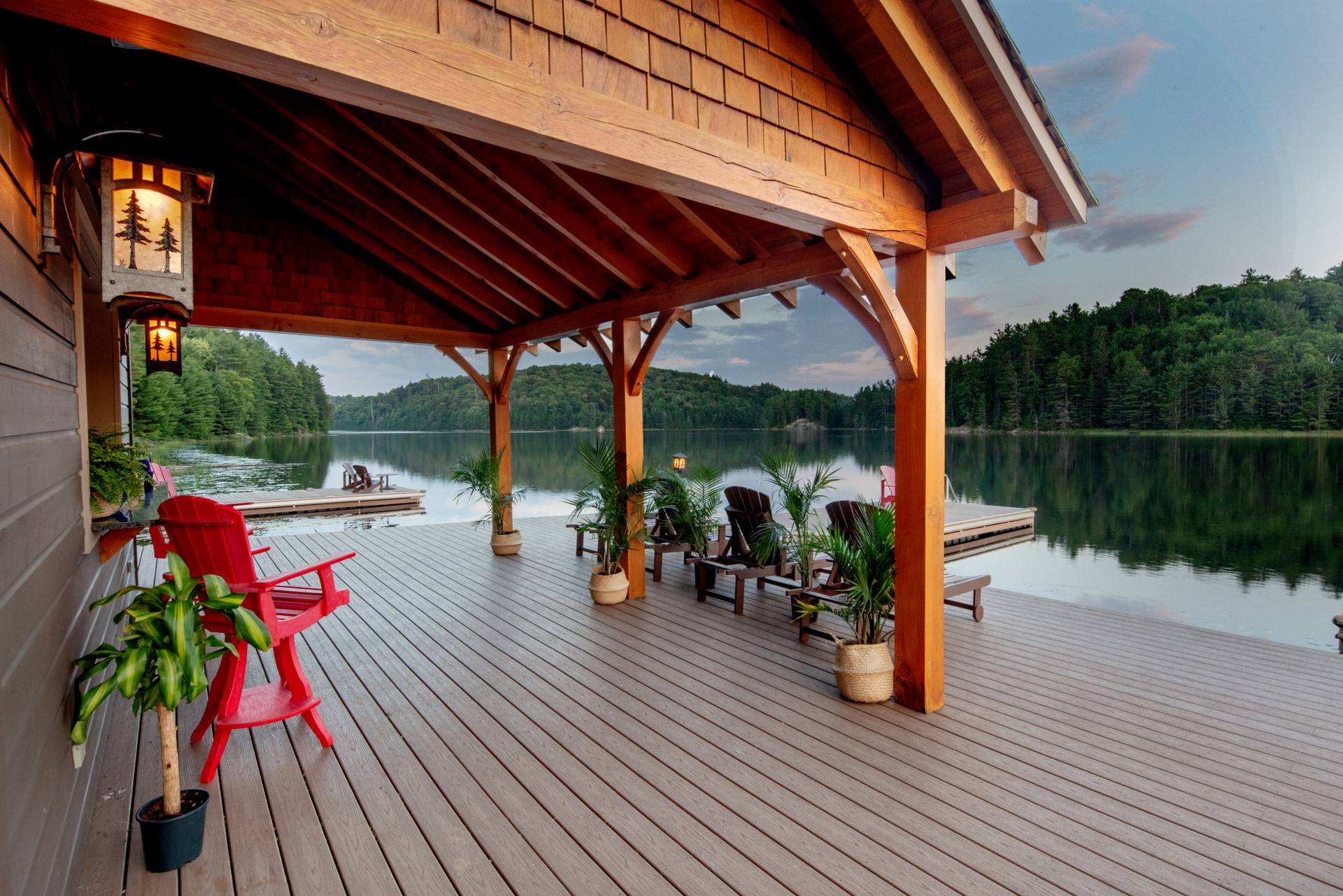 A wooden deck with chairs and a lantern overlooking a lake.