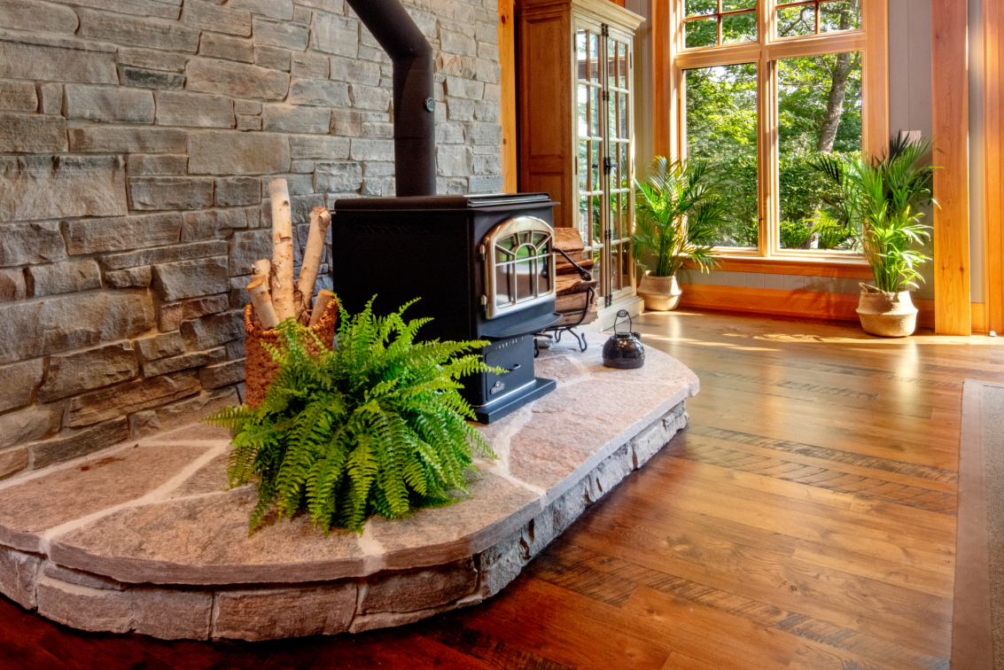 A wood stove is sitting on top of a stone fireplace in a living room.