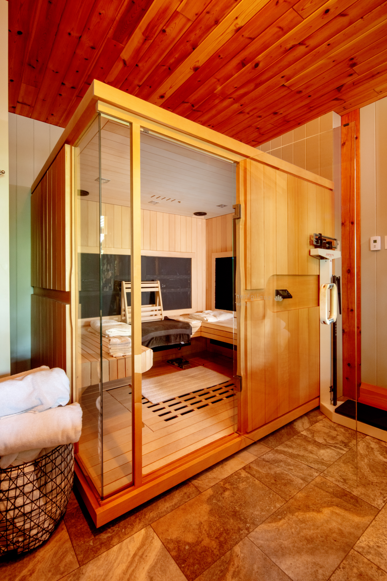 A bathroom with a sauna and a basket of towels