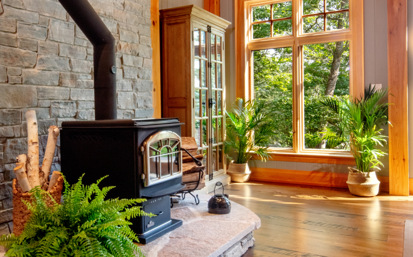 A wood stove is sitting in a living room next to a window.