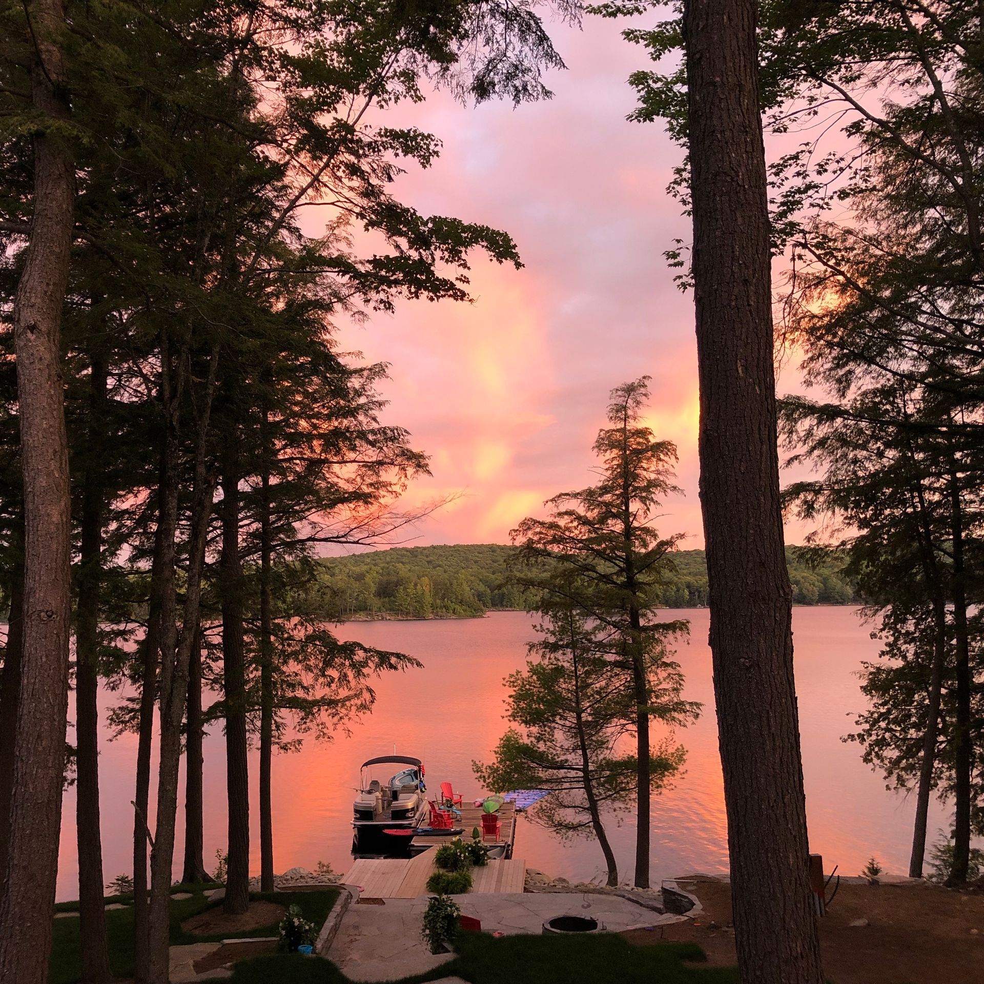 A wooden deck with chairs and a lantern overlooking a lake.