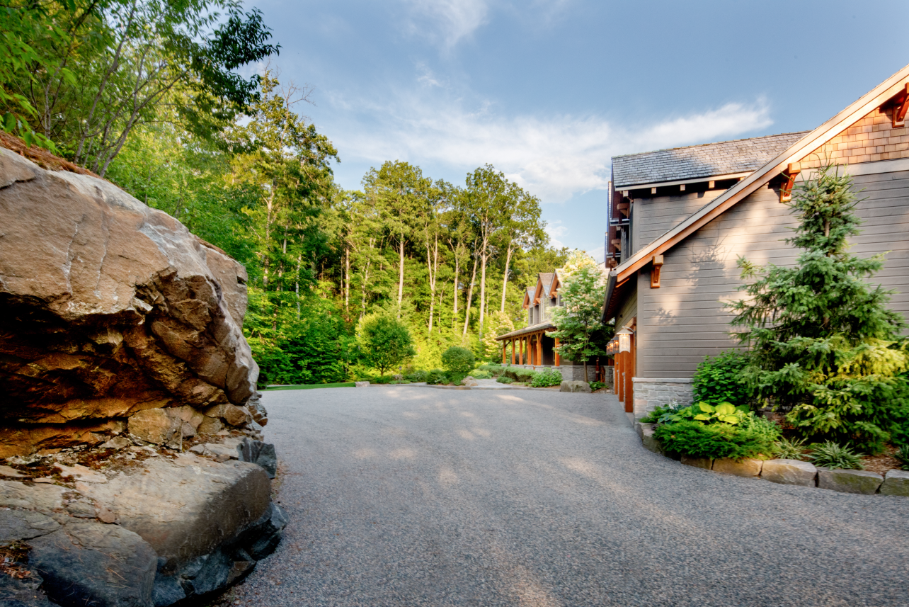 There is a large rock in the middle of the road in front of a house.