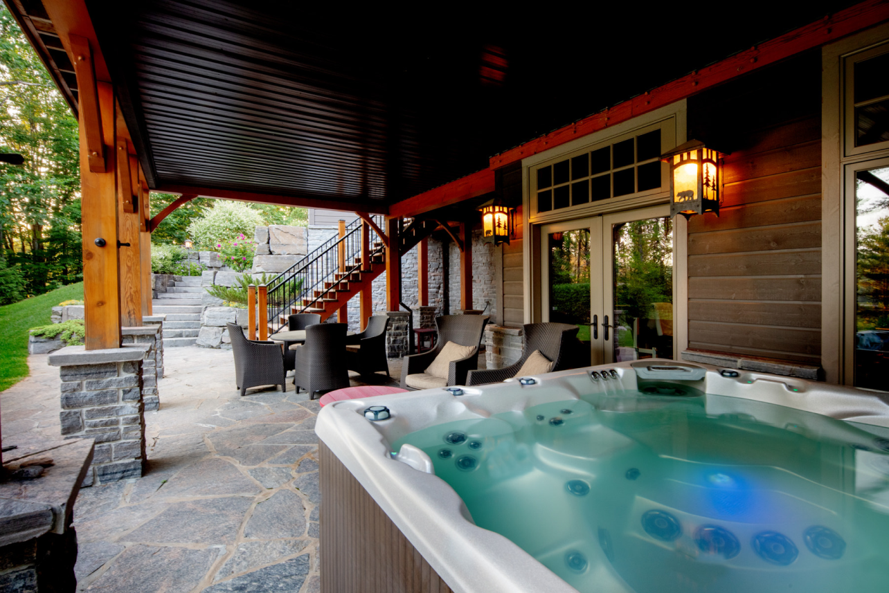 There is a hot tub on the patio of a house.