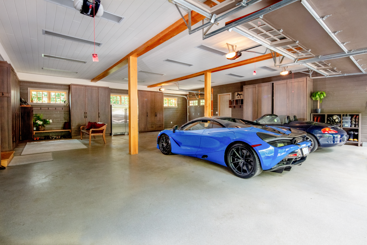 Two blue sports cars are parked in a large garage.