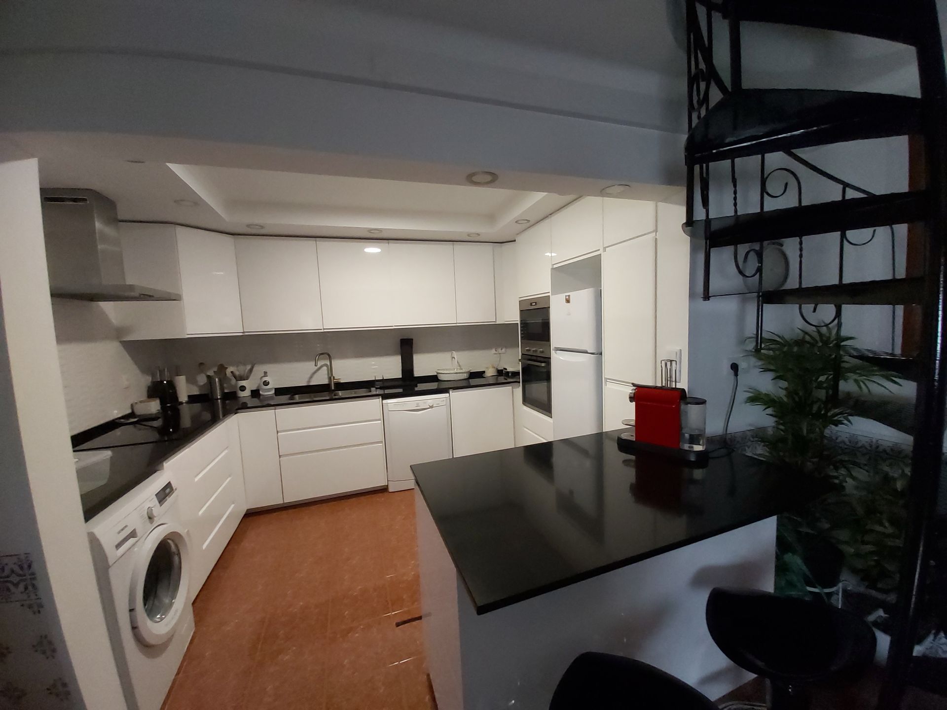 Uma cozinha com armários brancos e uma escada em espiral