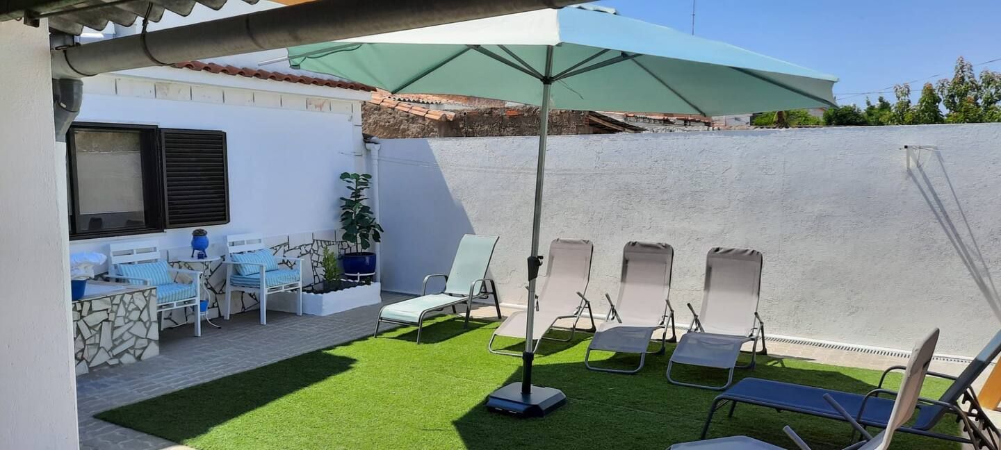 Um guarda-chuva verde está no topo de um gramado verdejante.