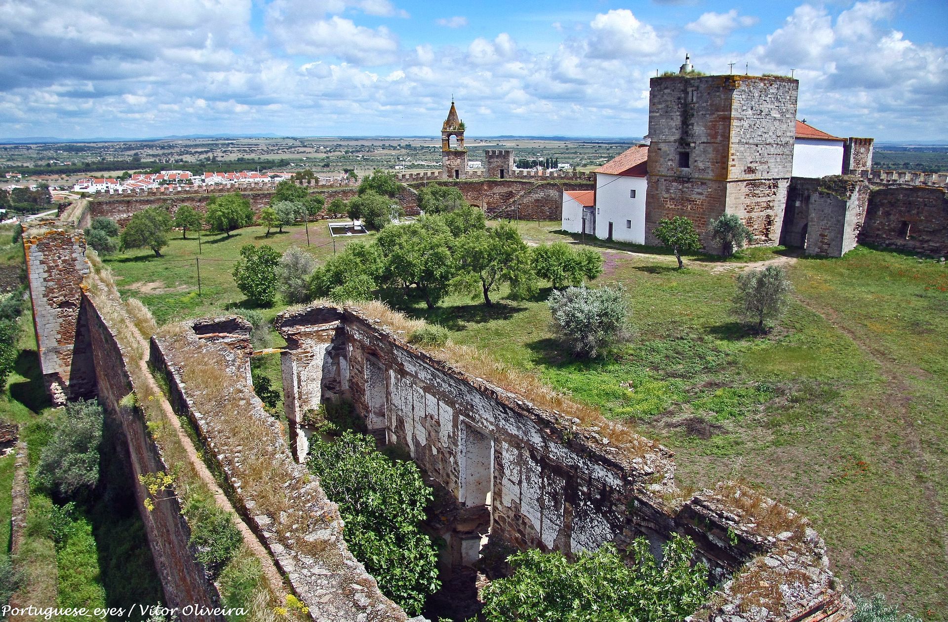 Uma vista aérea de um castelo com uma igreja ao fundo