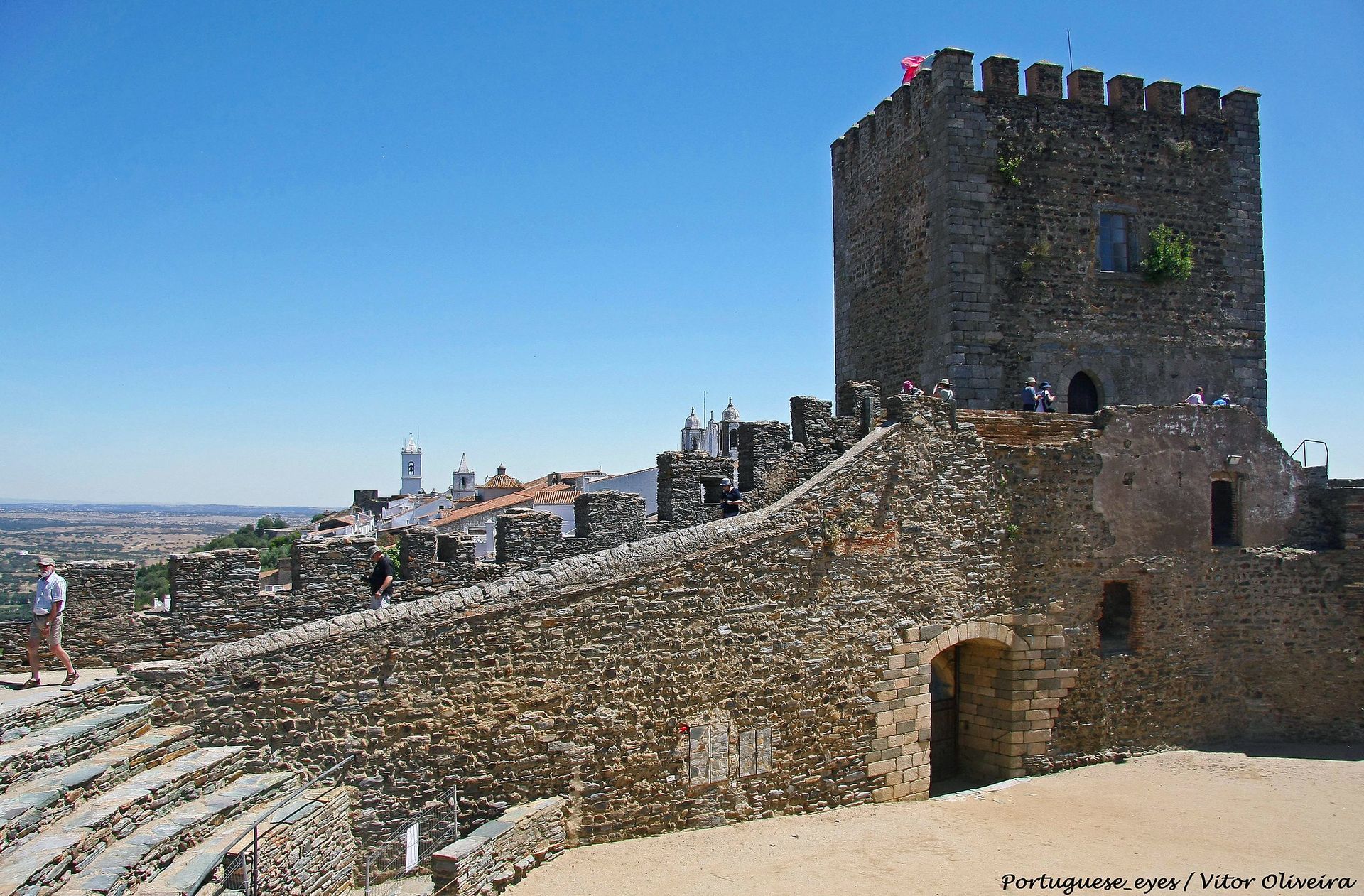 Um castelo com um muro de pedra e uma torre ao fundo