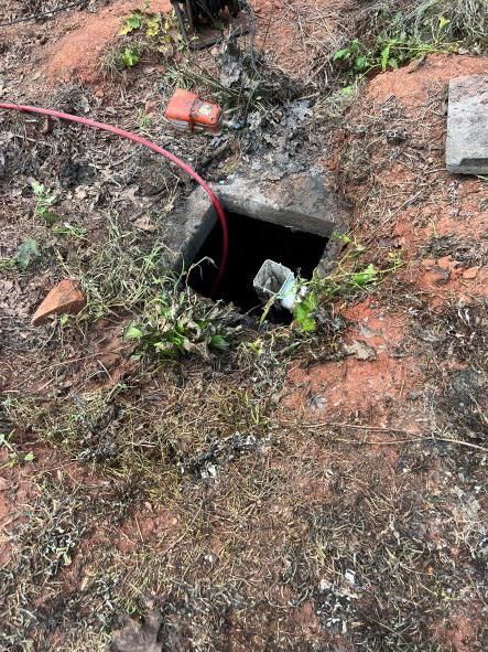 A hole in the ground with a red cord coming out of it.