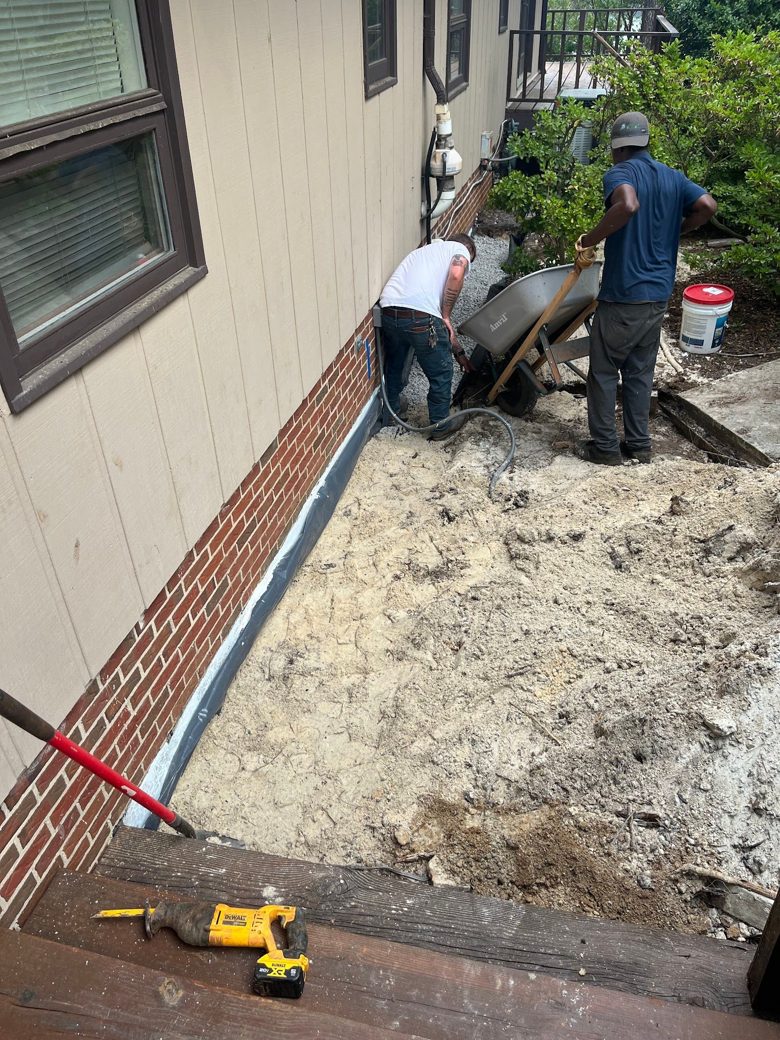 Two men are working on the side of a house.