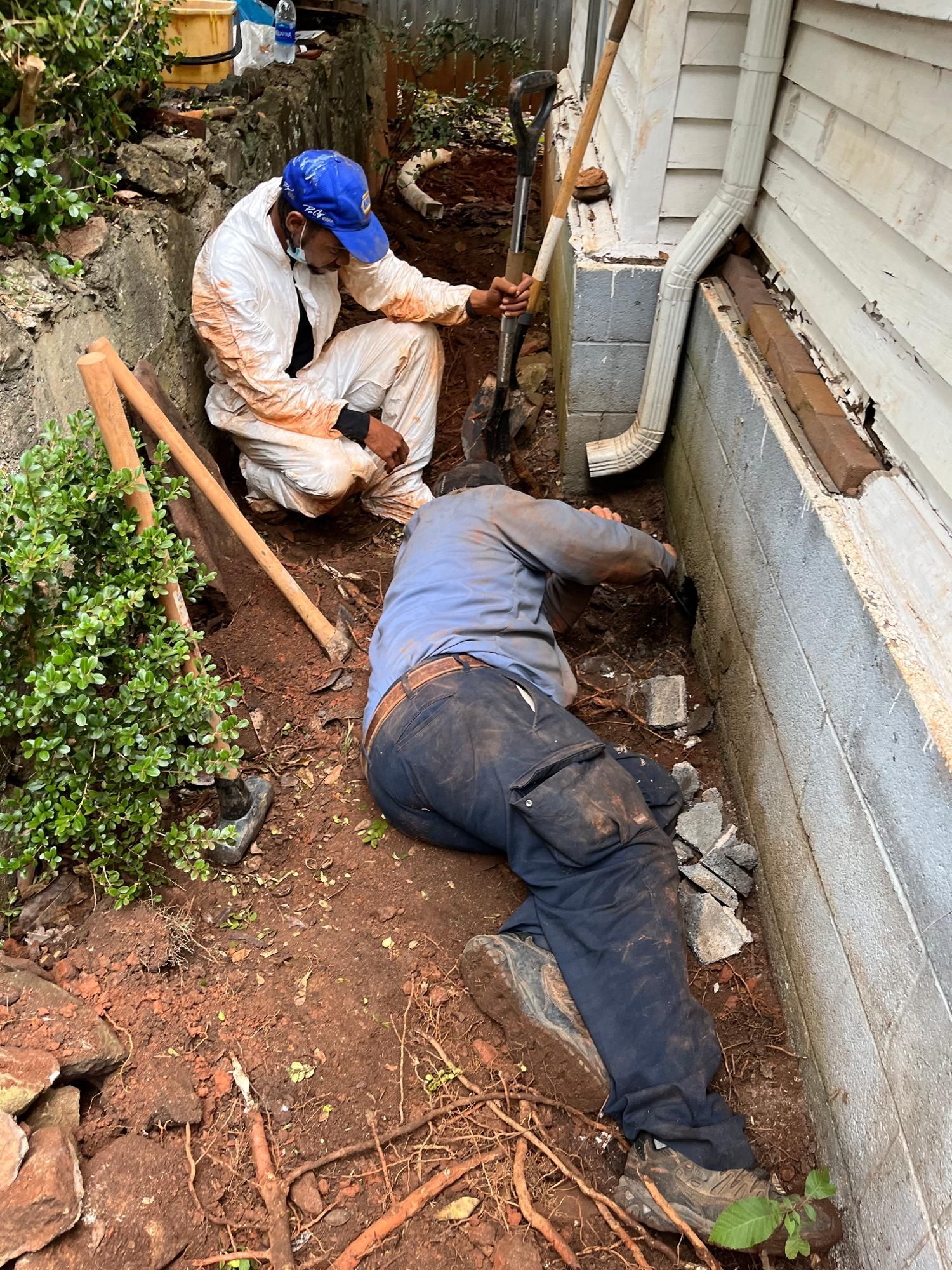 Two men are working on the foundation of a house.