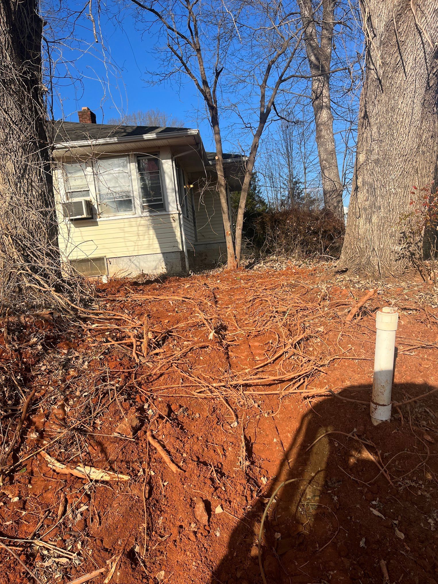 A house is sitting on top of a pile of dirt next to trees.