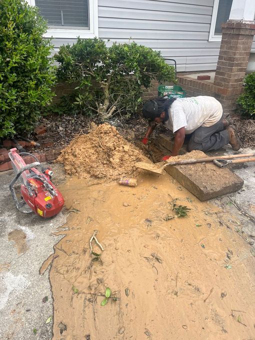 A man is kneeling down in the dirt in front of a house.