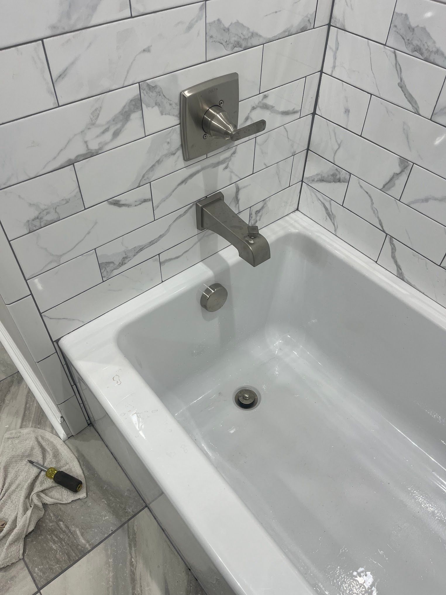 A bathtub in a bathroom with white tiles and a faucet.