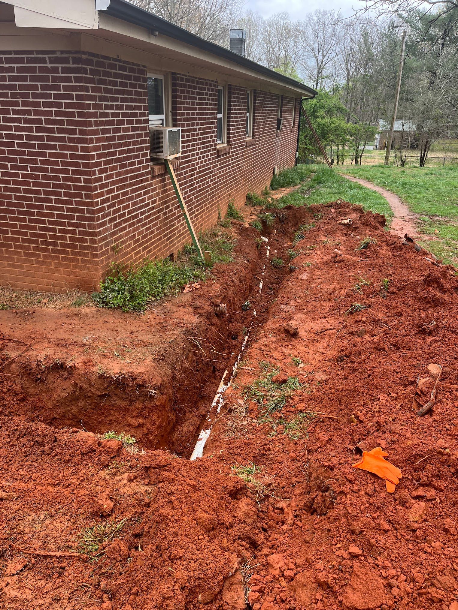 A large pile of dirt is in front of a brick house.