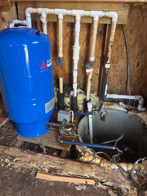A blue water tank is sitting next to a well in a room.