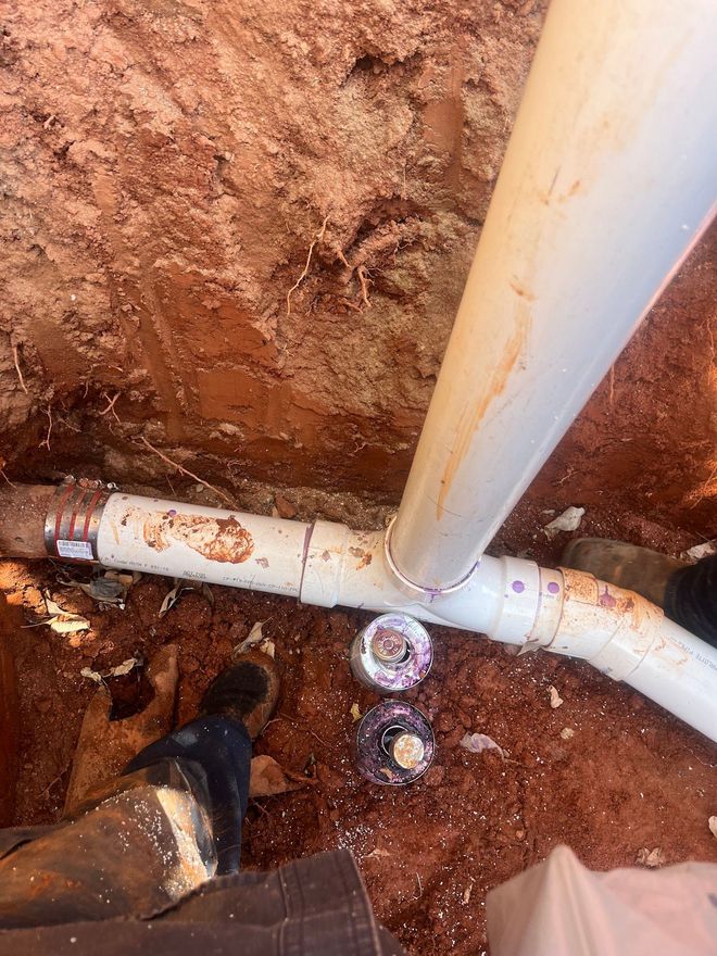 A person is standing next to a pipe in the dirt.