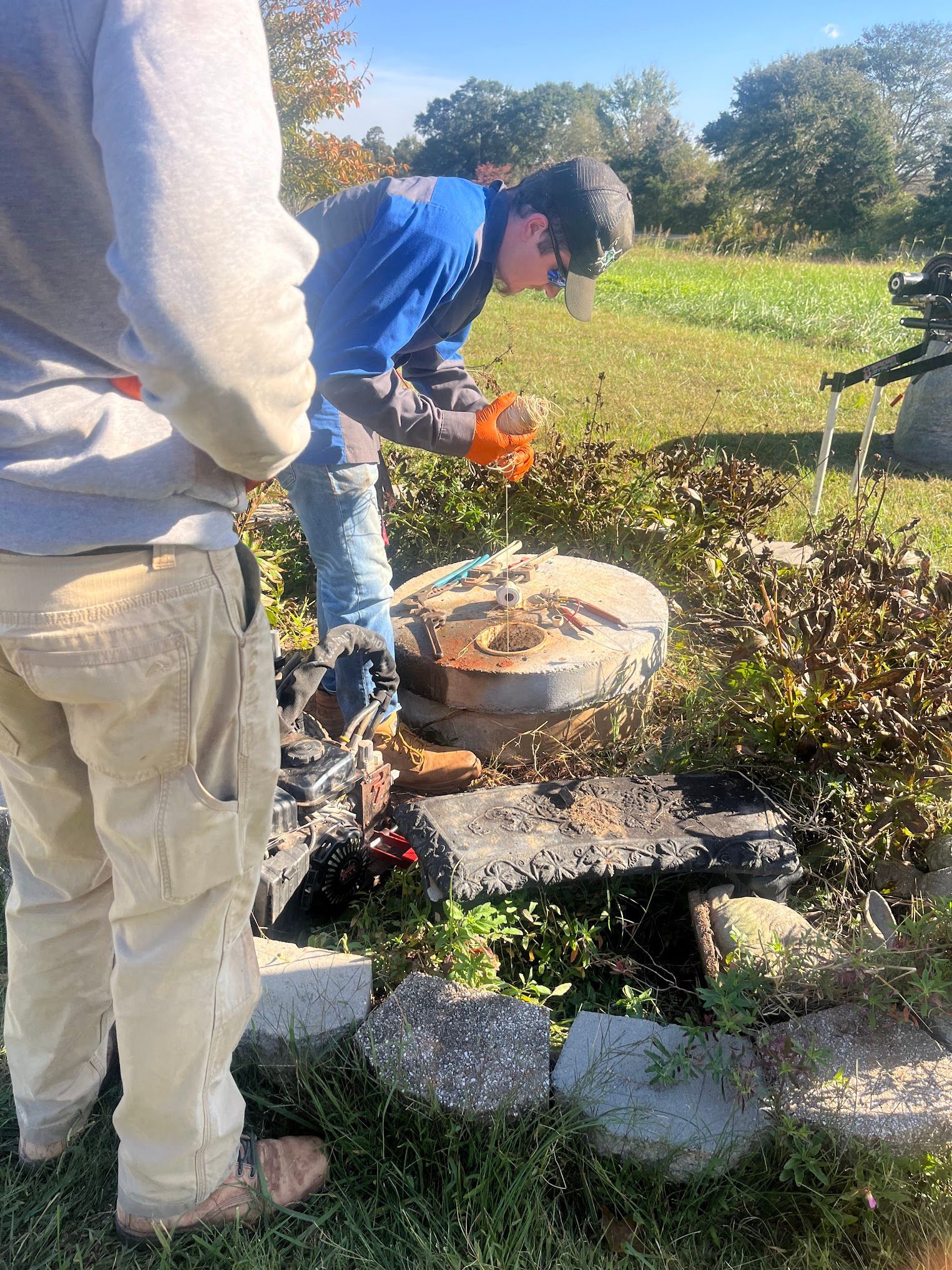 A man is drilling a hole in a rock in a field.